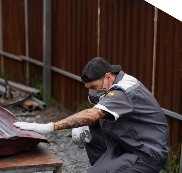 Worker inspecting metal sheet outdoors.